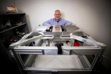 Brent Seales kneeling in front of machinery used for examining ancient Dead Sea Scroll fragments